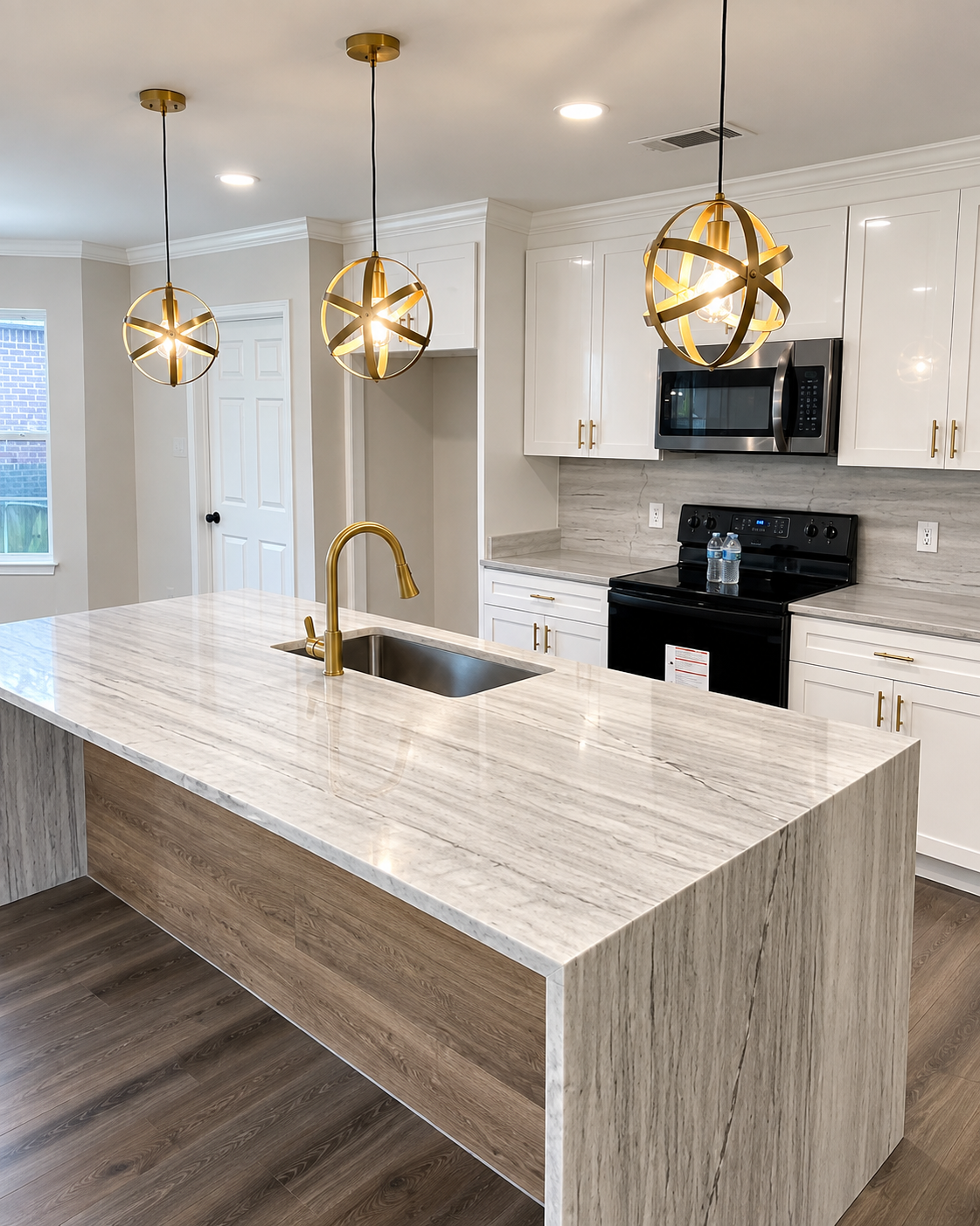 White kitchen cabinets with gold pendant lights and a waterfall island