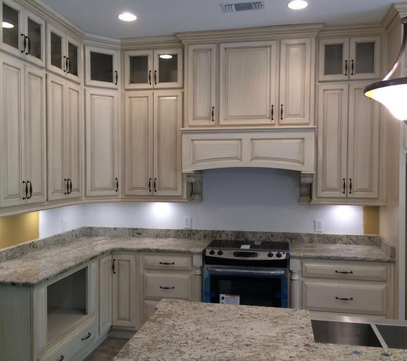 Painted kitchen cabinets with glass-front upper doors and patterned stone countertops